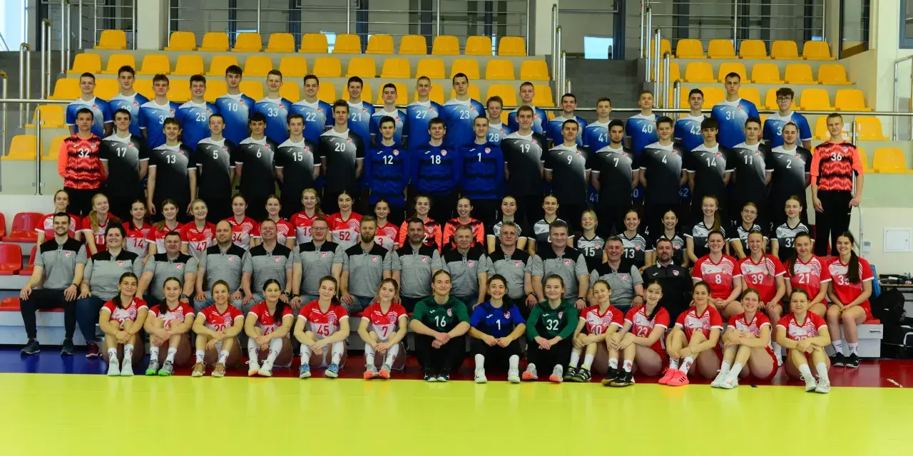 Drużyna siatkarska z numerami na strojach, w tym Marcin Markuszewski, pozuje do zdjęcia grupowego na tle żółtych trybun.
