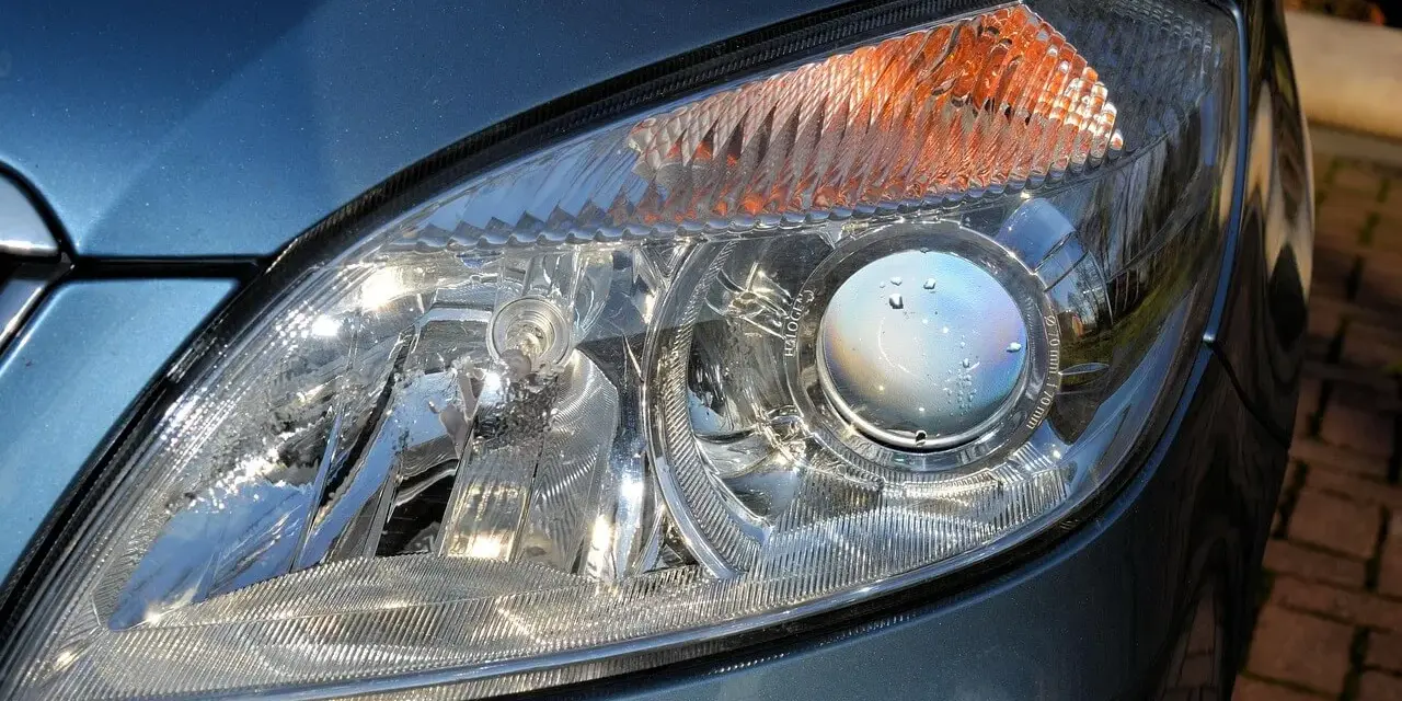 Zbliżenie na reflektor samochodu, gdzie widać soczewkę z kroplami wody. W tym miejscu znajdują się odpowietrzniki w reflektorach, zapobiegające parowaniu.