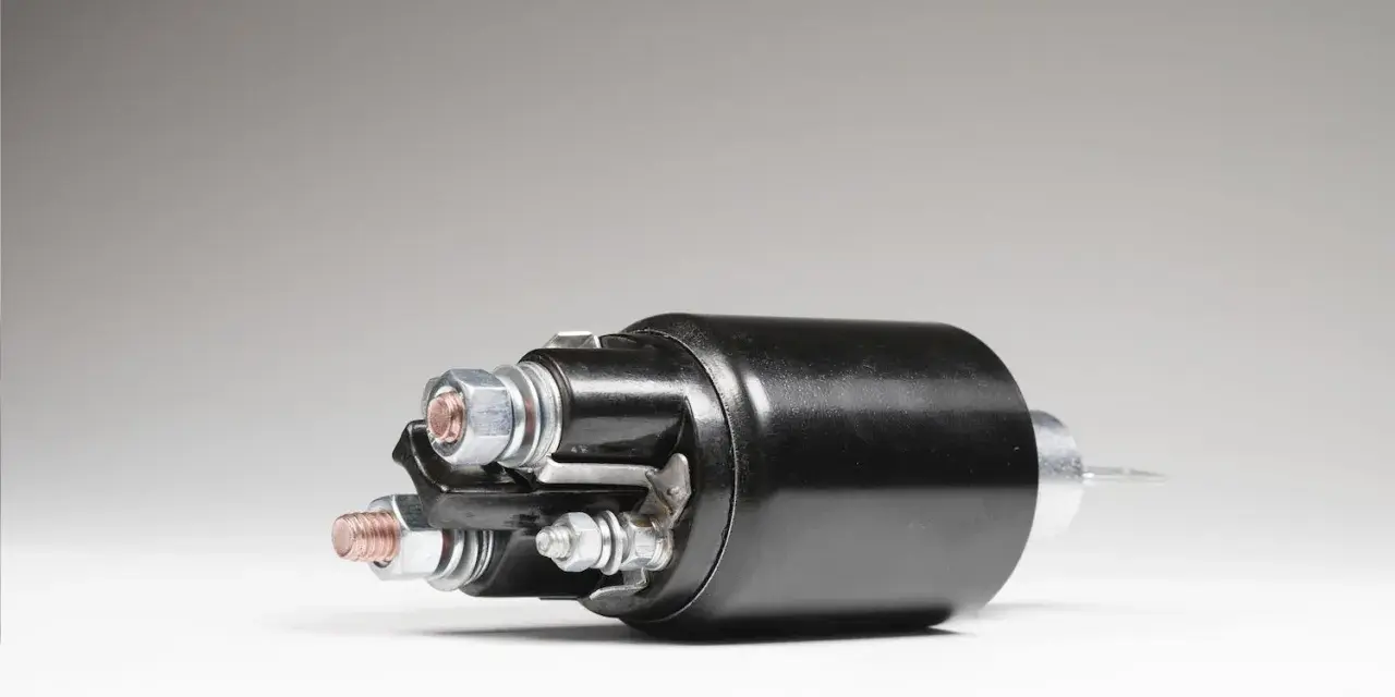 A black starter solenoid with copper and silver bolts, ready to power up an engine.
