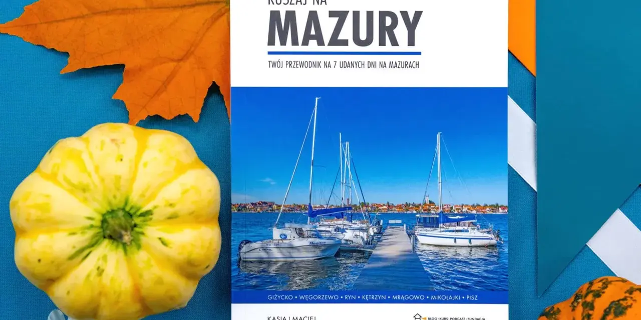 Przewodnik "Ruszaj na Mazury" z widokiem na żaglówki i miasteczko. Idealny na podróż po krainie tysiąca jezior.