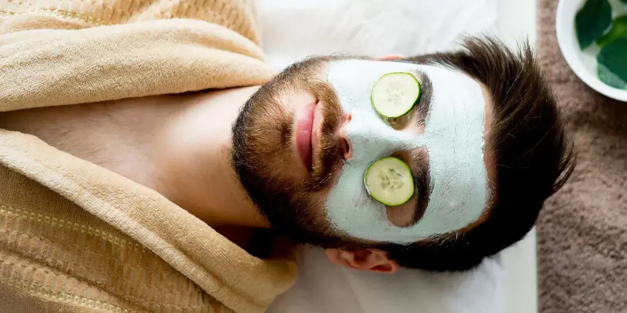 Man with a face mask and cucumber slices on eyes, relaxing. Wondering how long to keep face mask on for best results.