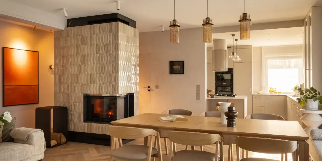 Przytulny salon z kominkiem i jadalnią w stylu klasycznym. Drewniany stół z krzesłami, kanapa i nowoczesny kominek tworzą ciepłą atmosferę.