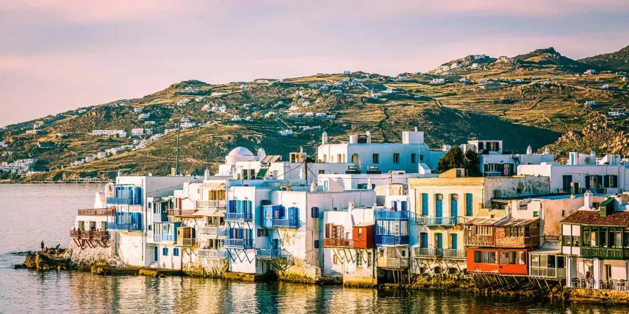 Charming waterfront houses with blue shutters, a classic view of places in Greece to visit.