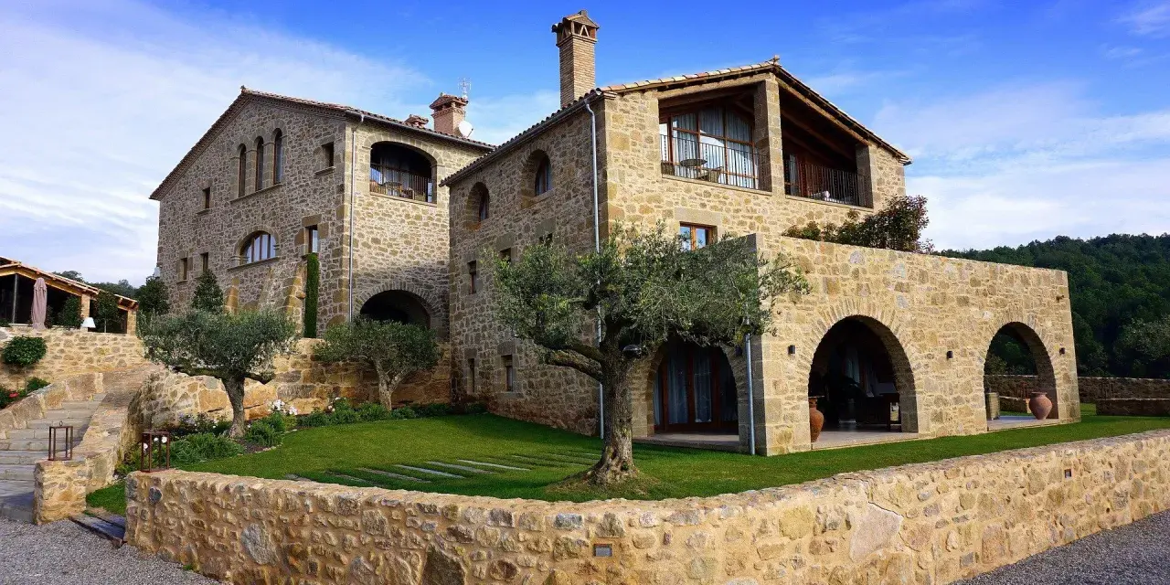 Magnifique maison en pierre calcaire avec des arches et un jardin verdoyant.