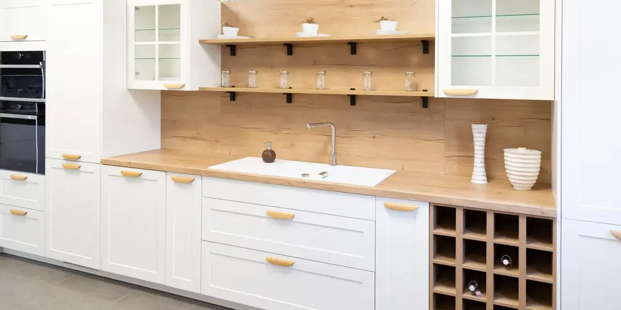 Cocina moderna blanca con encimera de madera, estantes flotantes y botellero. Inspiración para tus ideas de cocinas.