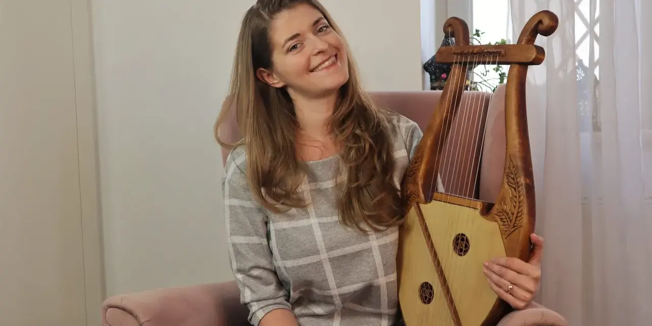 Uśmiechnięta kobieta trzyma instrument muzyczny, który wygląda jak skorupa żółwia.