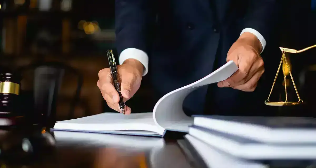 Un avocat examine des documents, une balance de la justice et un maillet sur un bureau. Il semble qu'il soit confronté à une situation où je ne peux pas payer la prestation compensatoire.