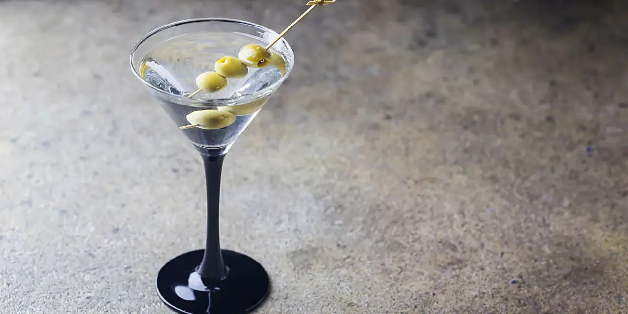 Klasyczny Dirty Martini przepis: schłodzony gin, wermut i oliwki na wykałaczce w eleganckim kieliszku.