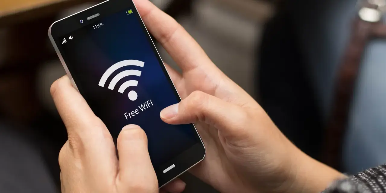 Dłonie trzymają smartfon z ikoną Wi-Fi i napisem "Free WiFi". Zastanawiasz się, co pobiera najwięcej internetu w telefonie?