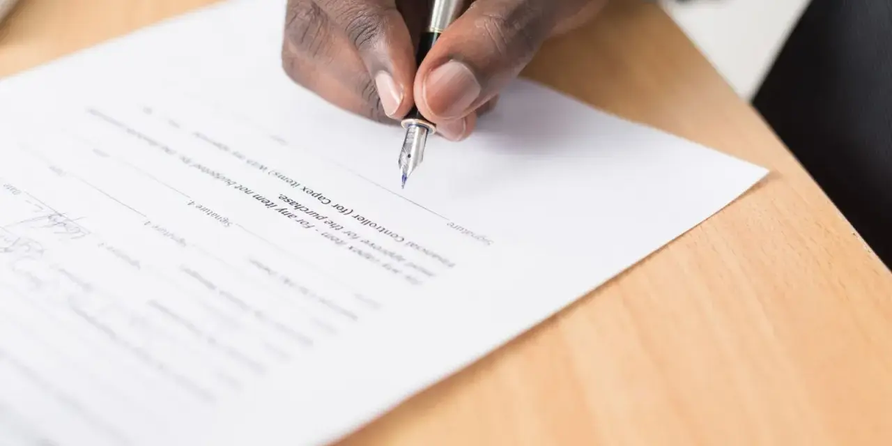 Main noire signant un document, peut-être pour éviter un trouble de jouissance.