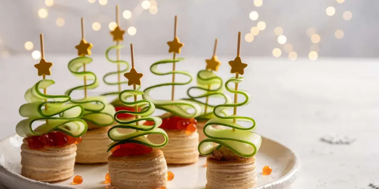 Aperitivos navideños en forma de árbol con pepino en espiral y estrellas doradas.