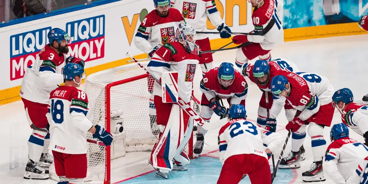 Czescy hokeiści w akcji podczas mistrzostw świata w hokeju 2024. Drużyna w białych strojach z czerwonymi i niebieskimi elementami walczy o zwycięstwo.