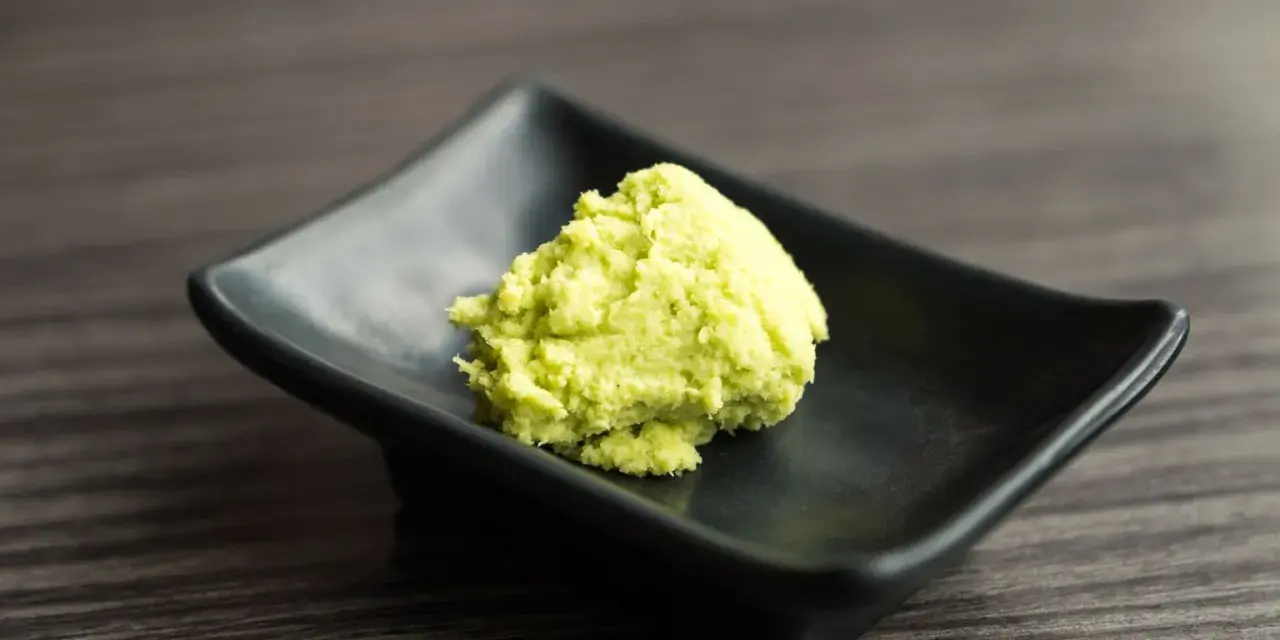Zielona pasta, czyli co to jest wasabi, na czarnej, kwadratowej miseczce.