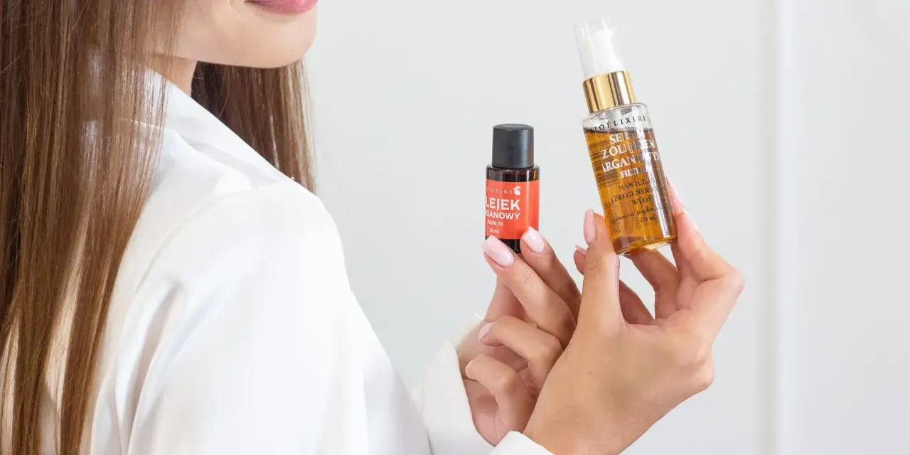 Kobieta prezentuje dwa produkty do pielęgnacji włosów, pokazując jak nakładać serum na włosy dla ich regeneracji i nawilżenia.