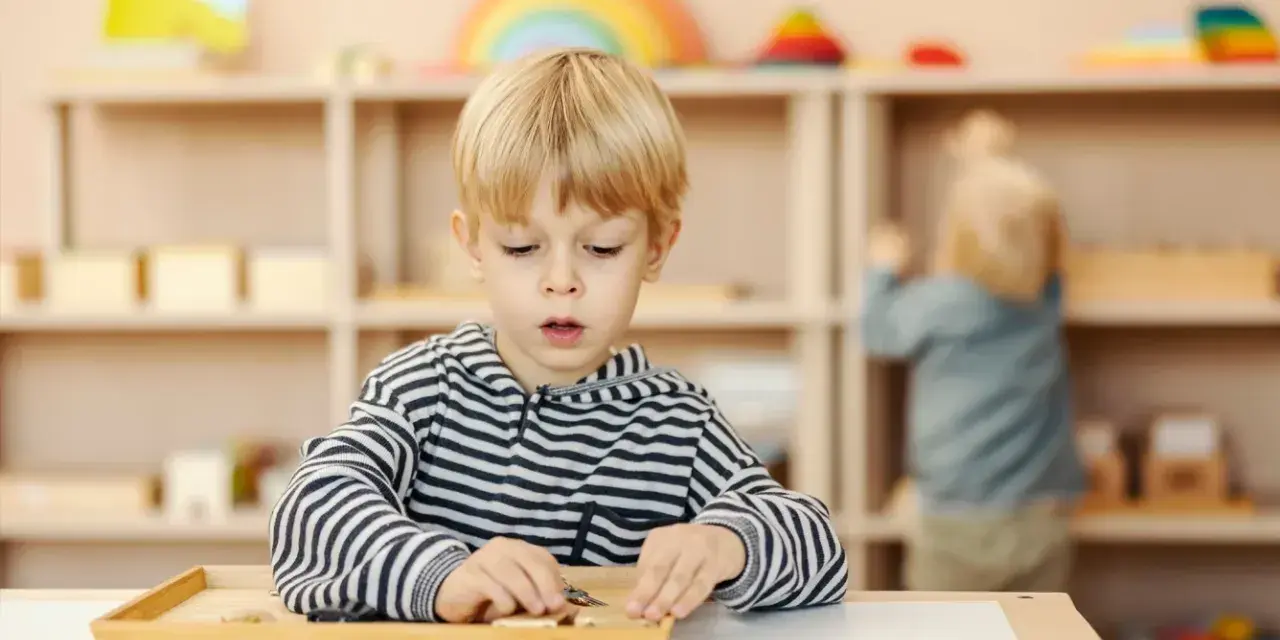 Chłopiec skupiony na zadaniu z materiałem Montessori. Ta metoda polega na samodzielnym odkrywaniu świata przez dziecko.