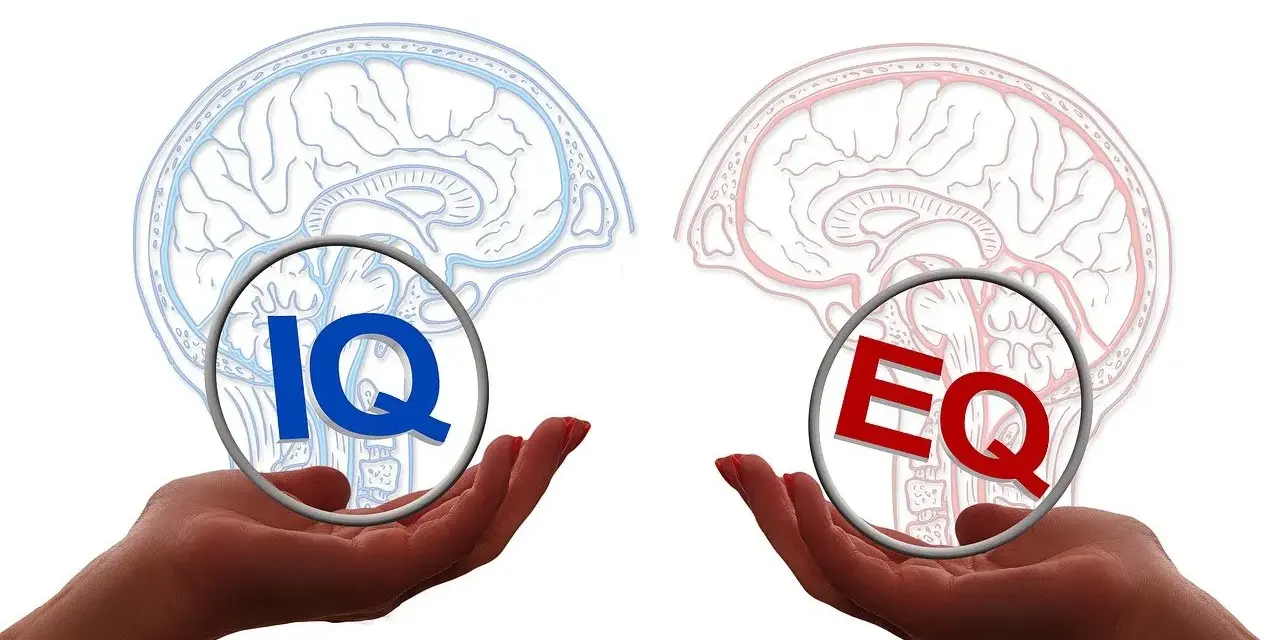 Dwie dłonie trzymają symbole IQ i EQ, symbolizujące równowagę między inteligencją a inteligencją emocjonalną.