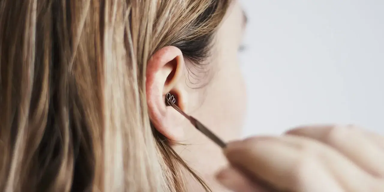 Une personne utilise un outil pour nettoyer son oreille. Les boules quies me font mal aux oreilles, alors je préfère cette méthode.