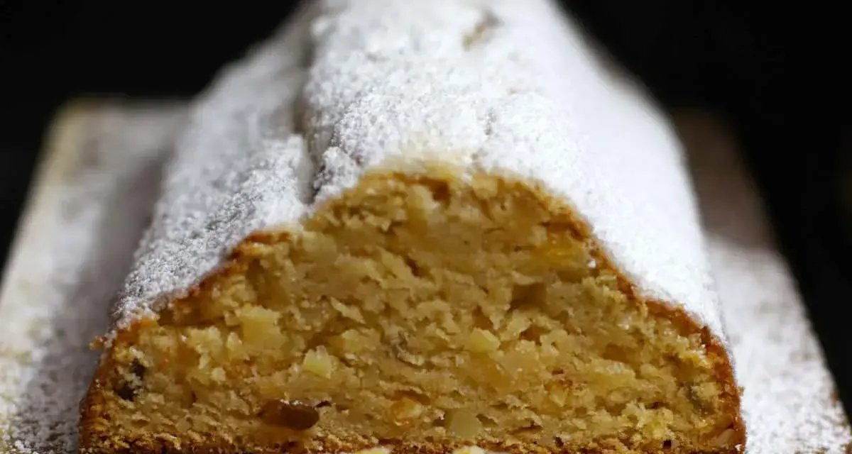 Ein saftiger Quarkstollen mit Marzipan, bestäubt mit Puderzucker, wartet auf den Anschnitt.