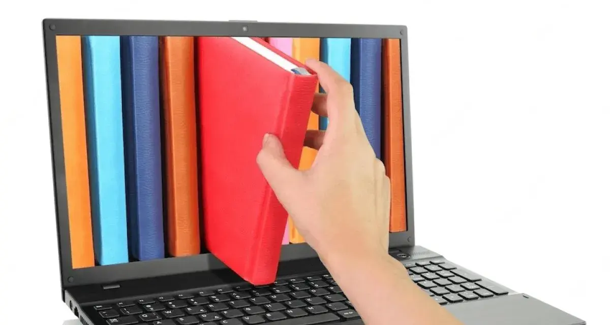Mano saca un libro rojo de una estantería digital en una laptop. Acceso a información y al libro de IVA.