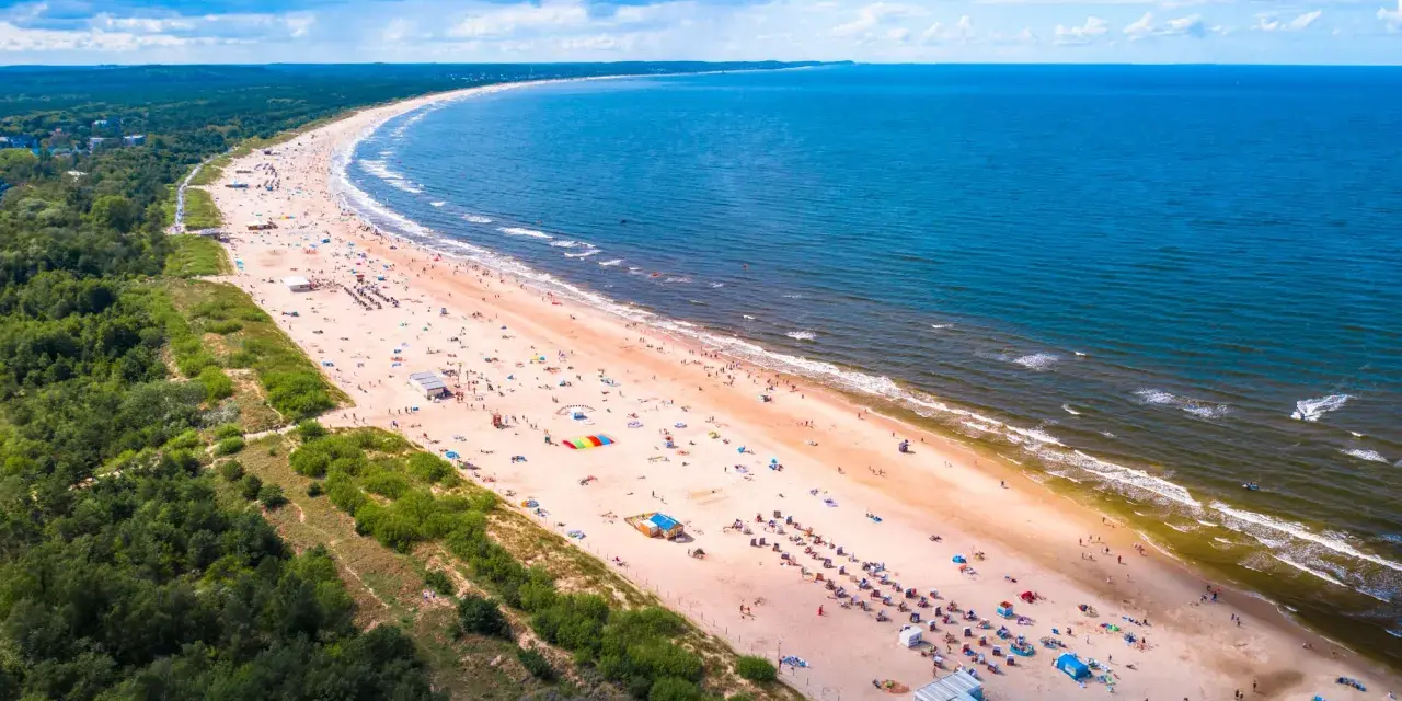 Szeroka, piaszczysta plaża z tłumem turystów, zielony las i błękitne morze – to jedne z najpiękniejszych plaż w Polsce.
