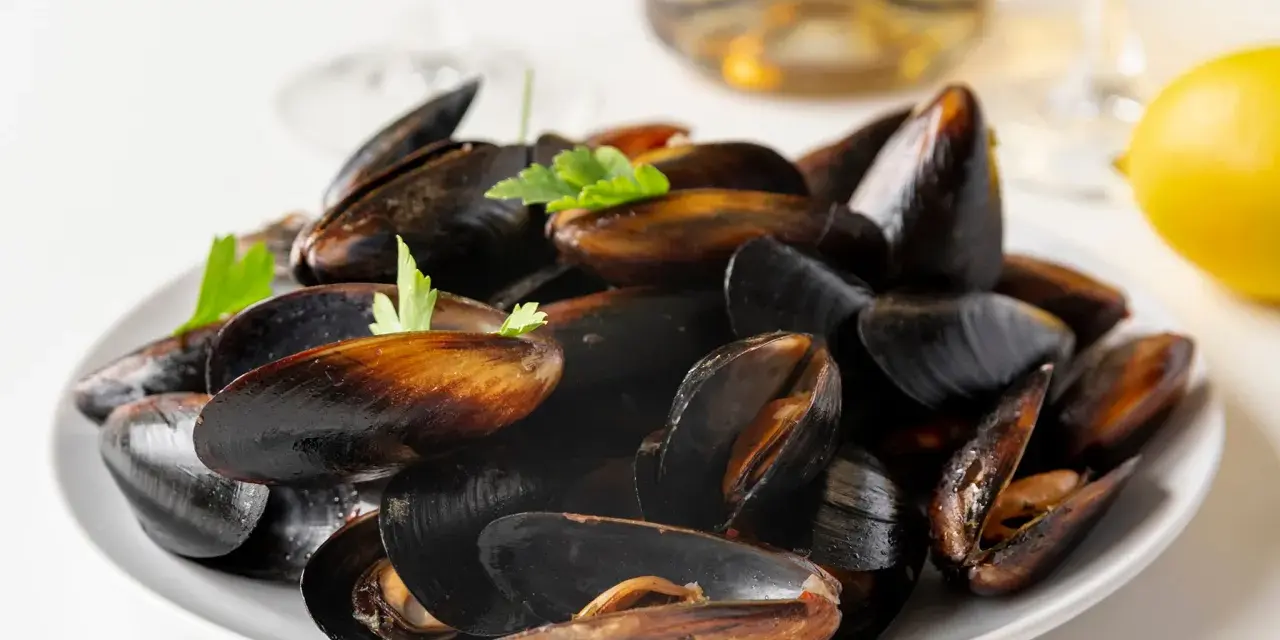 Plato de mejillones al vapor, listos para disfrutar con un toque de limón y perejil.