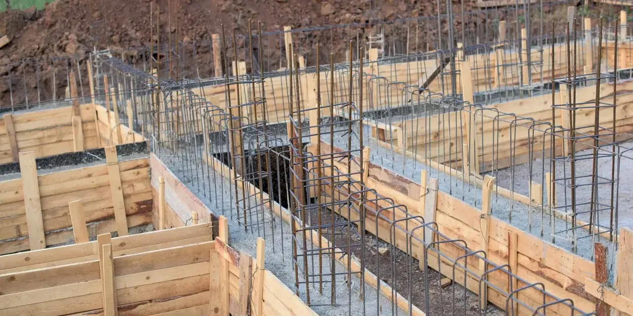 Drewniany szalunek fundamentowy z zbrojeniem stalowym, gotowy do wylania betonu.