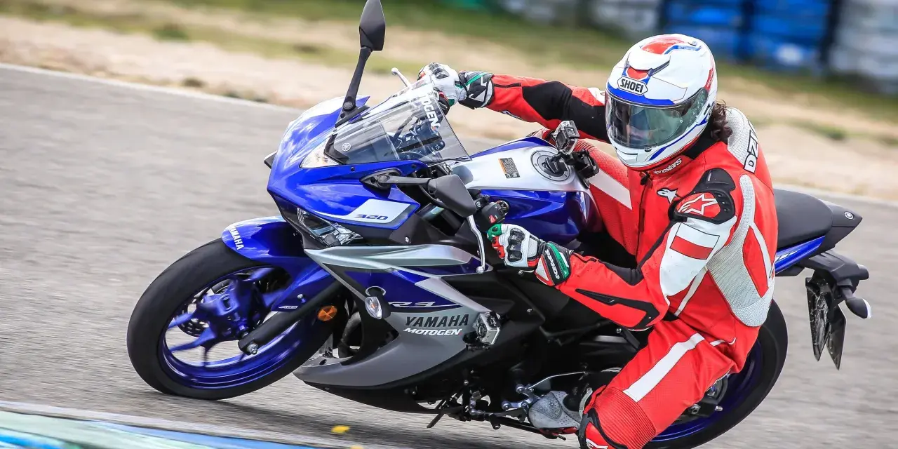 Motocyklista w czerwonym kombinezonie i kasku ściga się na torze na motocyklu Yamaha R3.