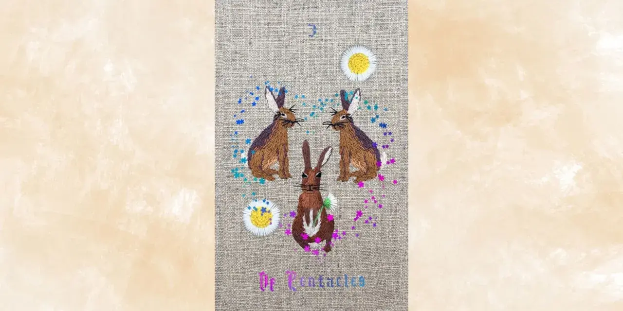 Tres conejos bordados, uno en el centro y dos a los lados, rodeados de flores y confeti. El número 3 y "De Pentaculos" escritos.