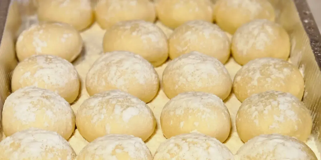 Piccolo pane fatto in casa, soffice e leggermente infarinato, pronto per essere infornato.