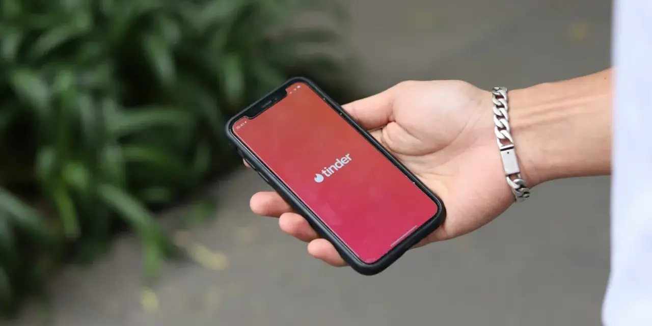 Dłoń trzyma smartfon z otwartą aplikacją Tinder. Zastanawiasz się, jak znaleźć osobę z Tindera na Facebooku?