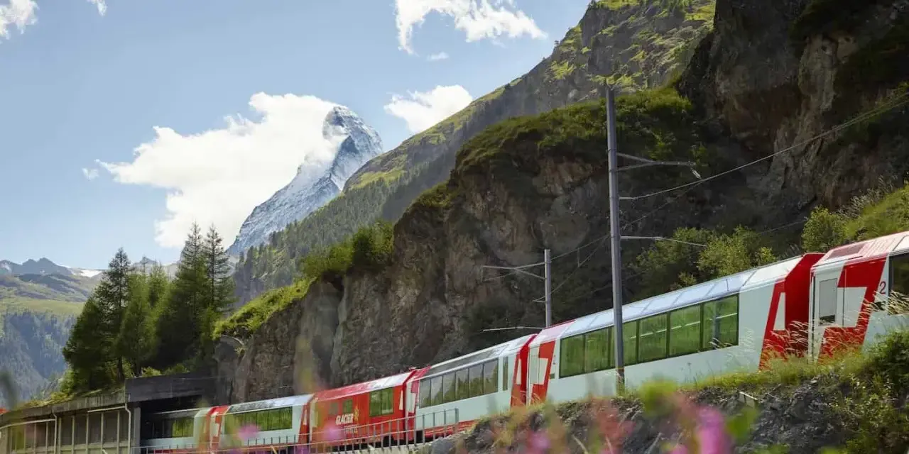 The Glacier Express train winds through the Swiss Alps, with the Matterhorn in the distance. Is the Glacier Express worth it? This view suggests yes!