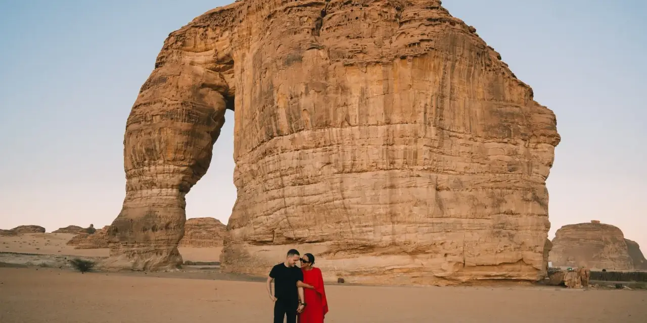 Coppia romantica davanti alla Roccia Elefante, una delle meraviglie naturali da vedere in Arabia Saudita.