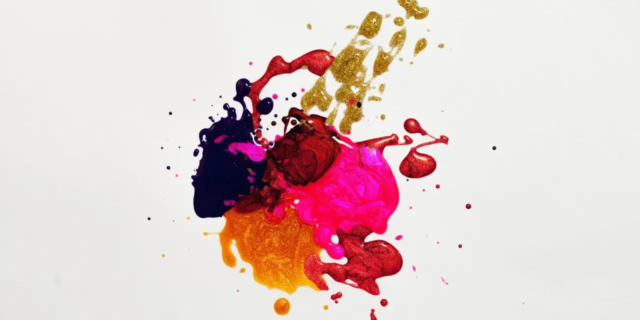 Salpicaduras de pintura vibrante en tonos morado, rosa, rojo y dorado, creando un patrón abstracto y dinámico sobre fondo blanco.
