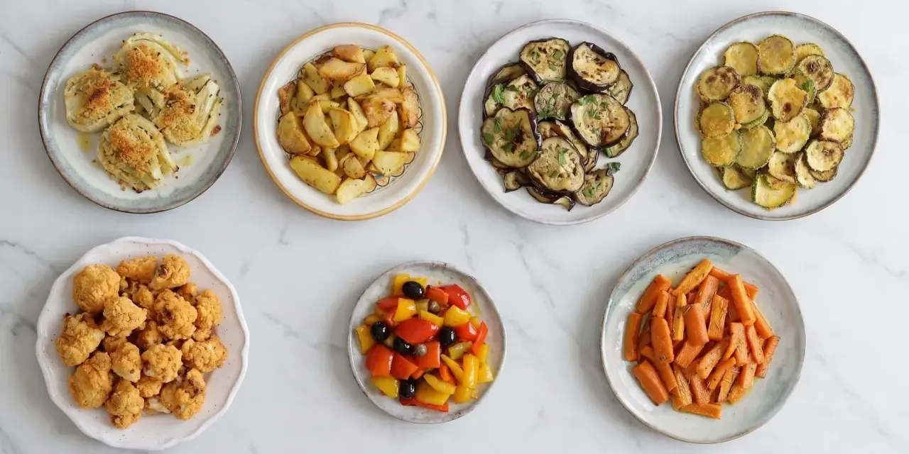 Sette piatti di verdure in friggitrice ad aria: finocchi, patate, melanzane, zucchine, cavolfiore, peperoni e carote.