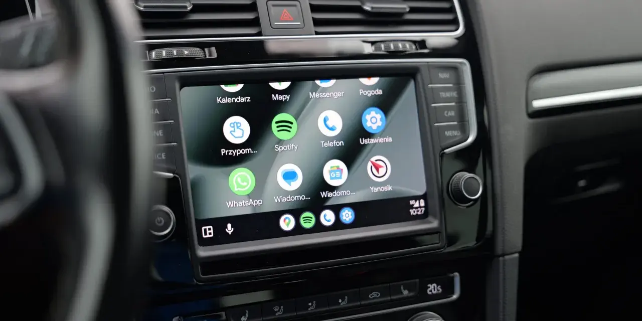 Ekran samochodu z widoczną aplikacją Android Auto, wyświetlającą ikony Kalendarz, Mapy, Spotify, WhatsApp i inne.