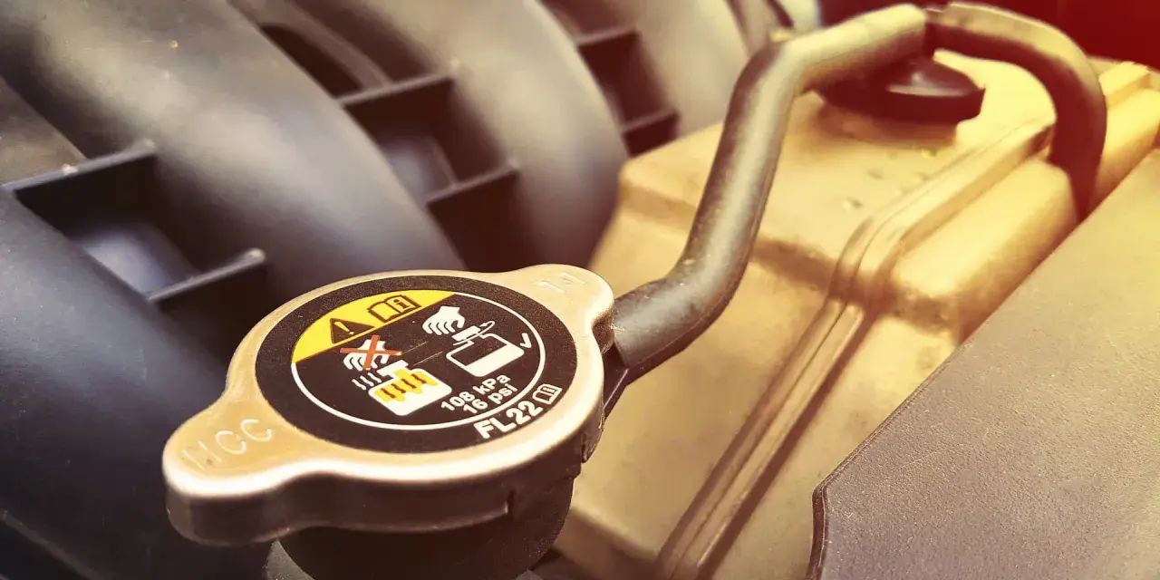 A car's radiator cap, showing warnings about hot coolant. A faulty cap can cause overheating, one of the bad radiator cap symptoms.