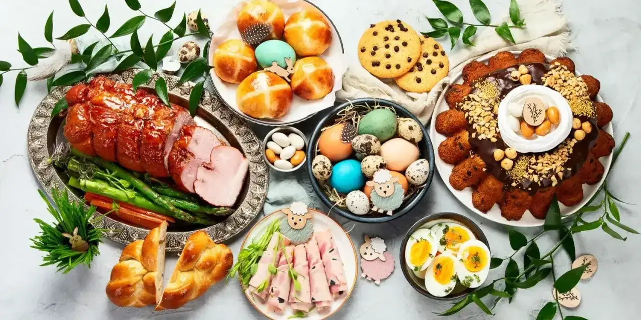 Wielkanocny stół pełen pyszności: pieczony schab, babka, pasztety, jajka, bułeczki i inne przekąski na wielkanoc.