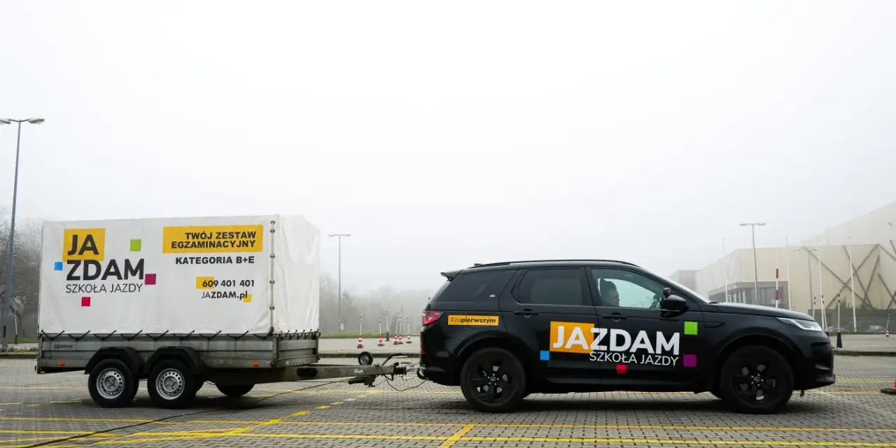 Czarny SUV z przyczepą szkoleniową "JA ZDAM" na placu manewrowym. Zestaw do kategorii B+E gotowy do egzaminu.