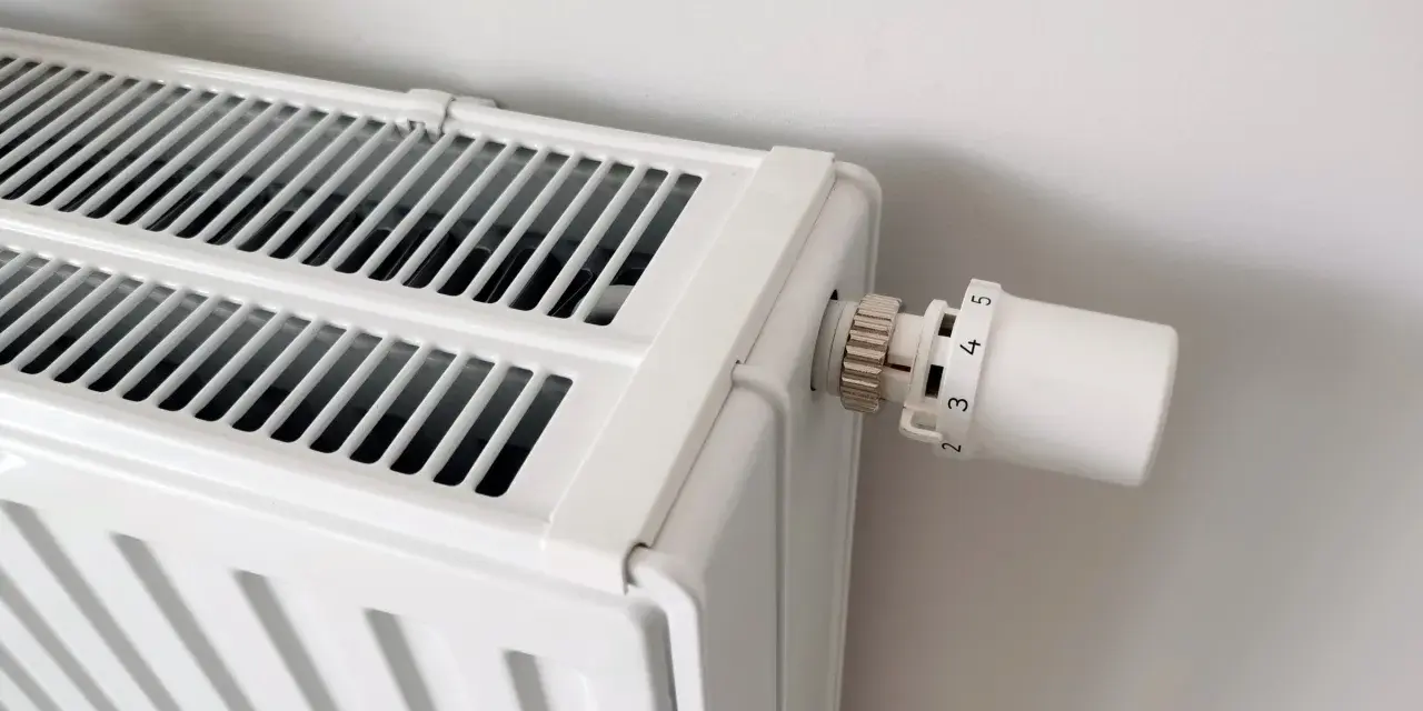 Biały grzejnik z termostatem. Dowiedz się, jak odpowietrzyć grzejnik, gdy przestaje efektywnie grzać.