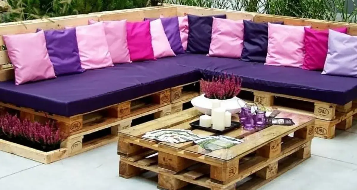 Narożna sofa i stolik kawowy z palet, ozdobione kolorowymi poduszkami i wrzosem. Prawdziwe cuda z palet!