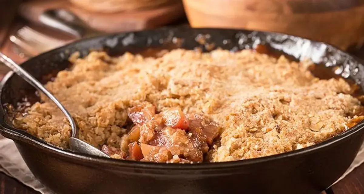 Un délice de pâte à crumble croustillante sur un lit de fruits fondants, servi dans une poêle en fonte.
