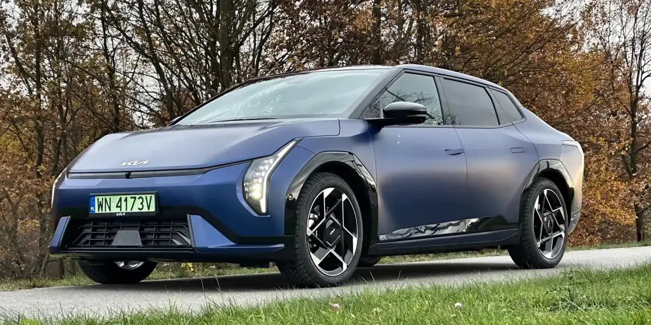 Niebieski Polestar 2 na tle jesiennych drzew. Elegancki samochód elektryczny z charakterystycznymi światłami i felgami.