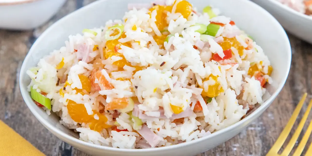 Omas Reissalat mit Orangenstücken, Schinkenwürfeln und Frühlingszwiebeln in einer Schüssel.