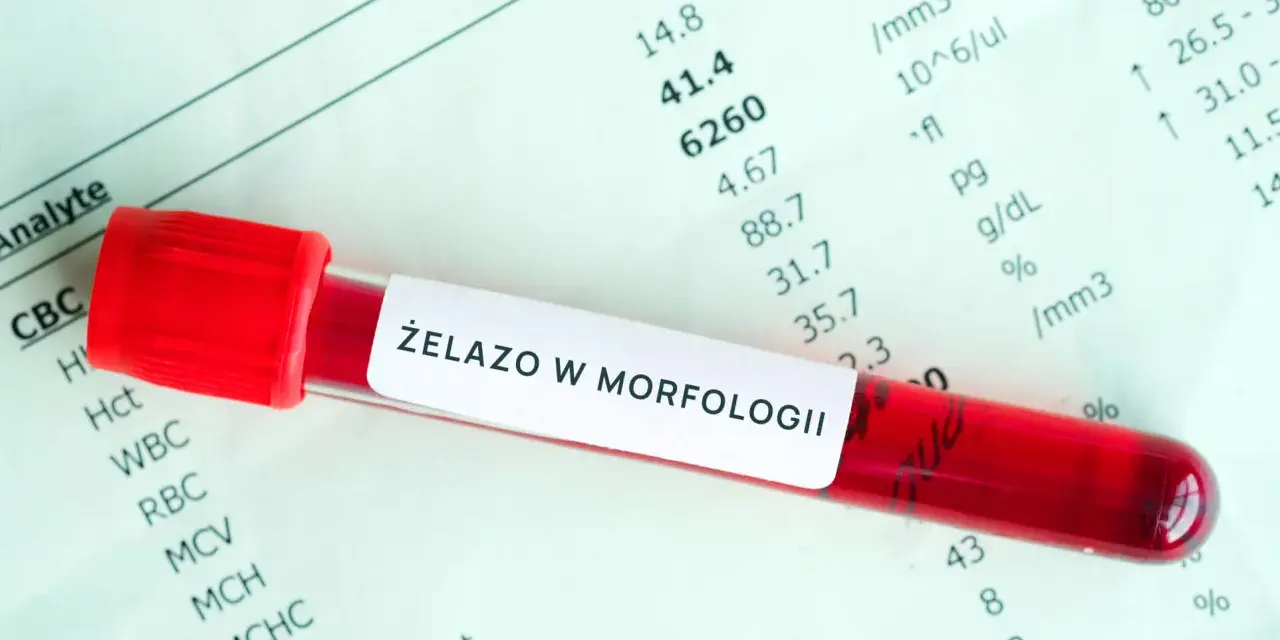 Czerwona probówka z krwią na tle wyników morfologii krwi z oznaczeniem "Żelazo w morfologii".