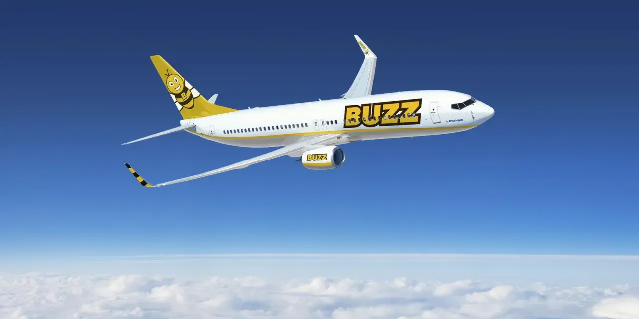 Samolot Buzz, należący do Ryanair, leci nad chmurami. Idealny na wakacje, zabierze Twój bagaż w słoneczne miejsce.