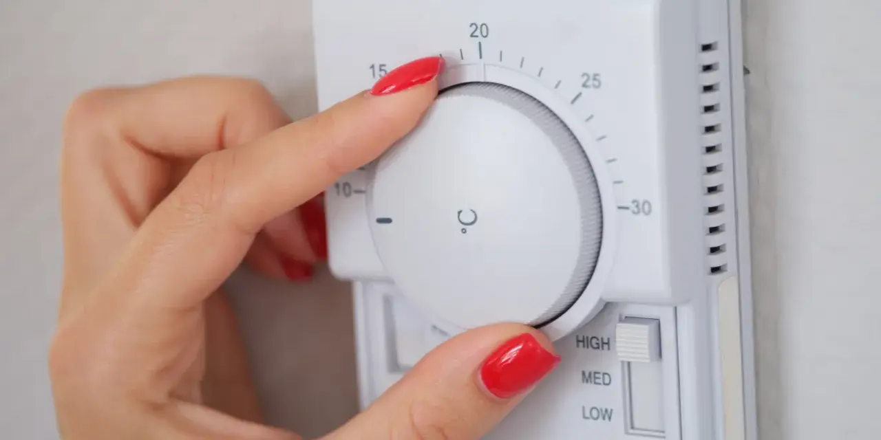 Dłoń z czerwonym lakierem reguluje termostat, ustawiając temperaturę dla elektro zaworów do CO.