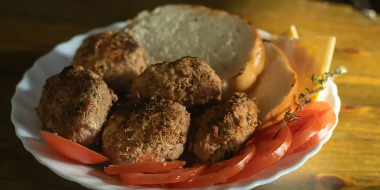 Talerz z kotletami mielonymi, kromkami chleba, pomidorami i serem. Idealny posiłek, jeśli zastanawiasz się, jaki kotlet mielony kcal.