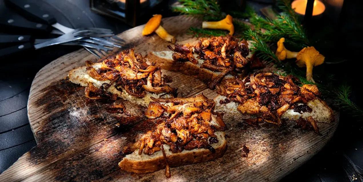 Smörstekta kantareller på bröd, ett enkelt och gott kantareller recept. Serveras på en träbricka med ljus och granris.