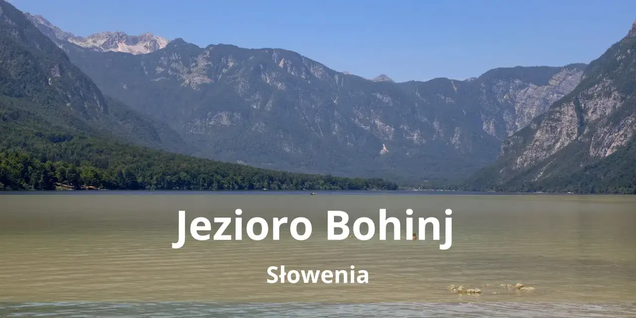 Spokojne jezioro Bohinj w Słowenii otoczone zielonymi wzgórzami i skalistymi górami.