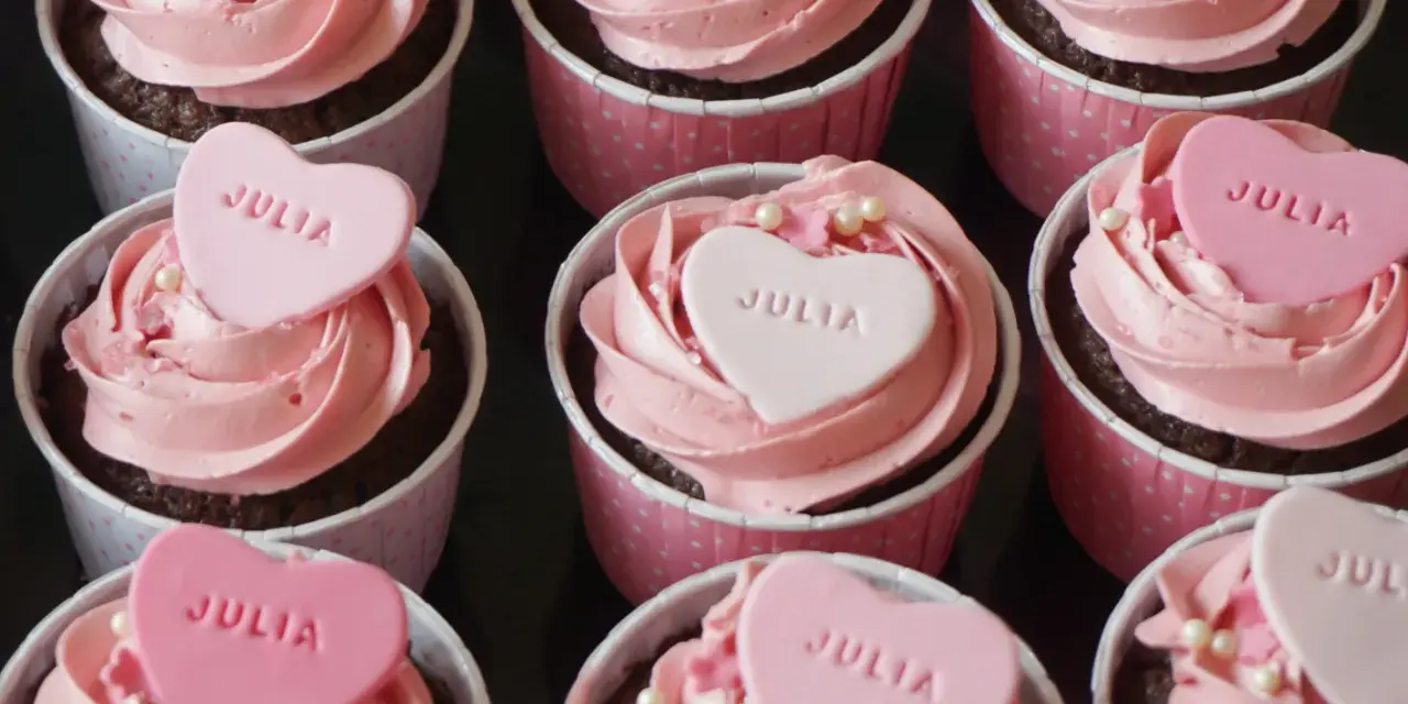 Rosa cupcakes med hjärtformade dekorationer med texten "JULIA". Perfekt för en speciell Julia!